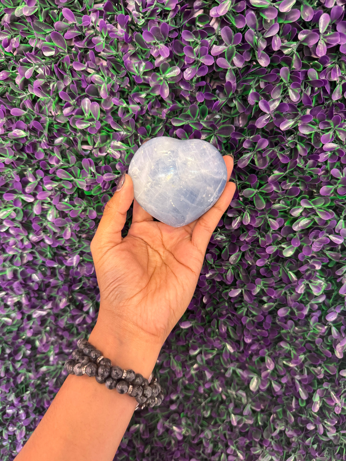 Pale Blue Heart Palm Stone — product photo 3. A smooth, puffy heart-shaped palm stone in soft pale blue, with cloudy white markings.