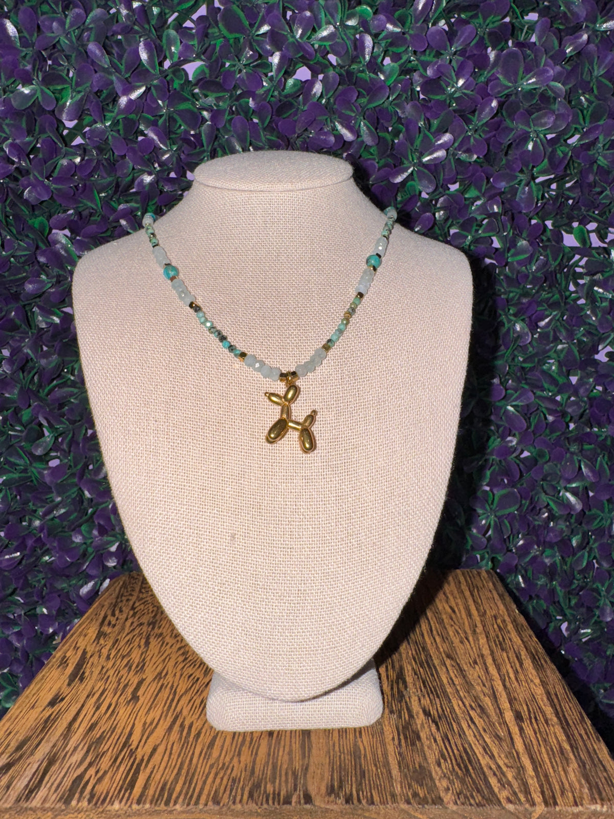 Balloon Dog Charm Necklace — product photo 1. A gold-tone balloon dog charm on an aqua faceted bead chain with gold-tone spacers.