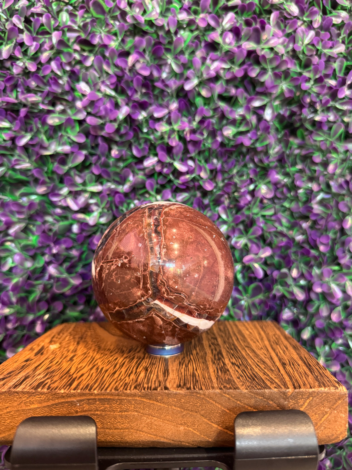 Side view of the red jasper sphere showing white breccia veining.