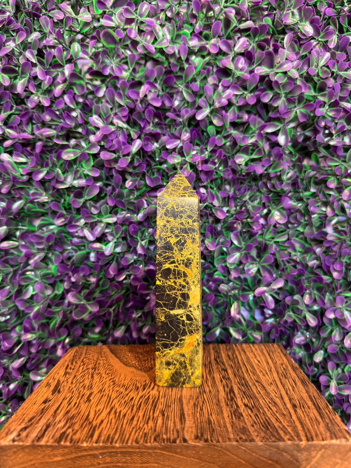 Yellow black and orange bumblebee jasper tower on a wood block.
