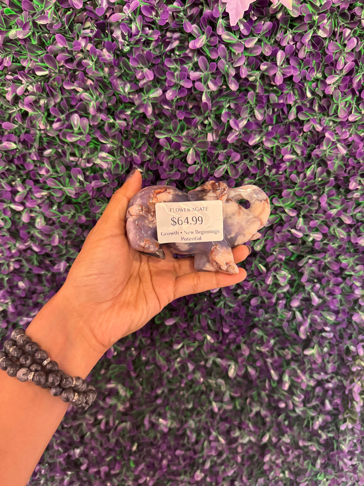 Flower agate elephant held in hand with a tag reading FLOWER AGATE and $64.99.