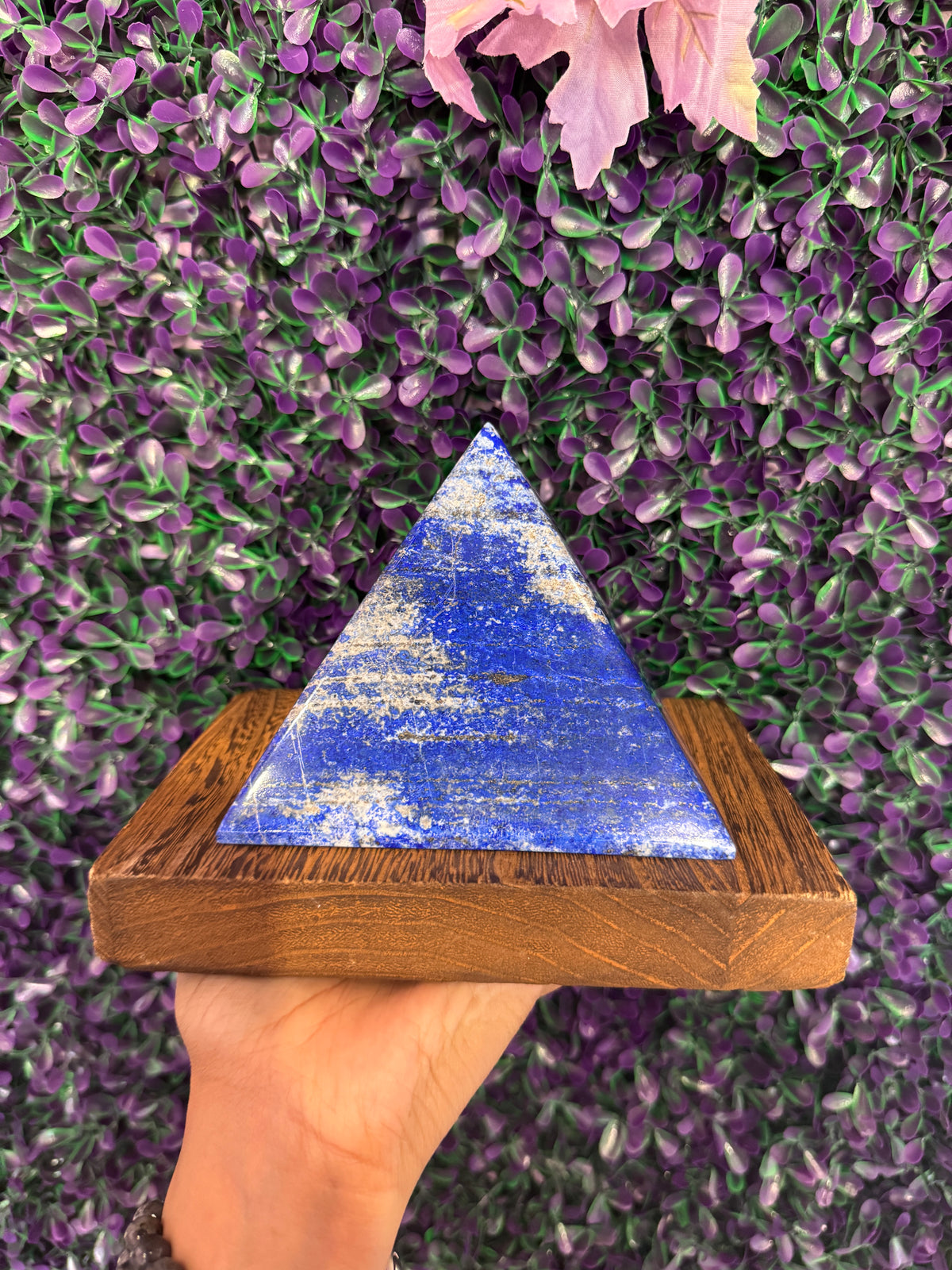 Deep blue lapis lazuli pyramid showing pyrite flecks on a wood block.