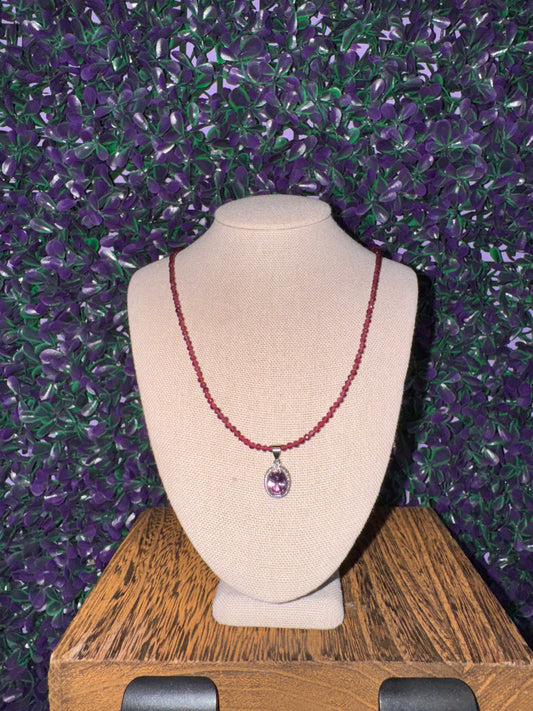 Lavender Oval Halo Pendant Necklace — product photo 1. A faceted lavender oval pendant in a silver-tone halo setting with clear accents, paired with a deep red faceted bead chain.