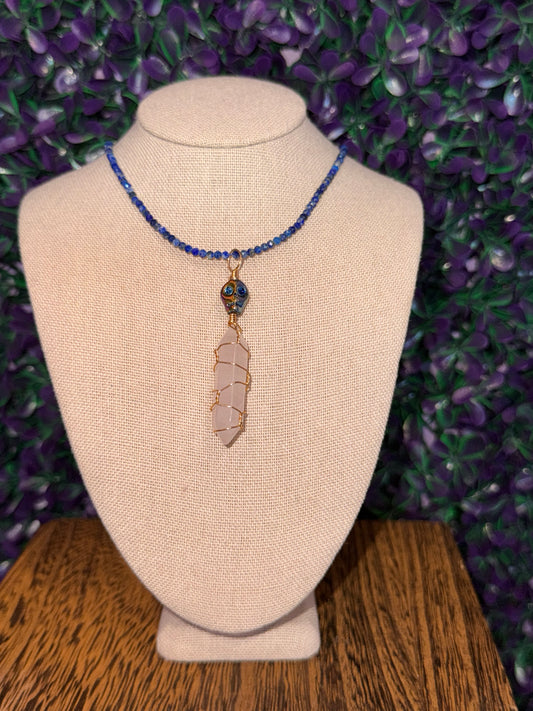 Pink Point and Skull Bead Necklace — product photo 1. A pale pink point wrapped in gold-tone wire, accented with a blue-and-gold skull bead and a blue faceted bead chain.