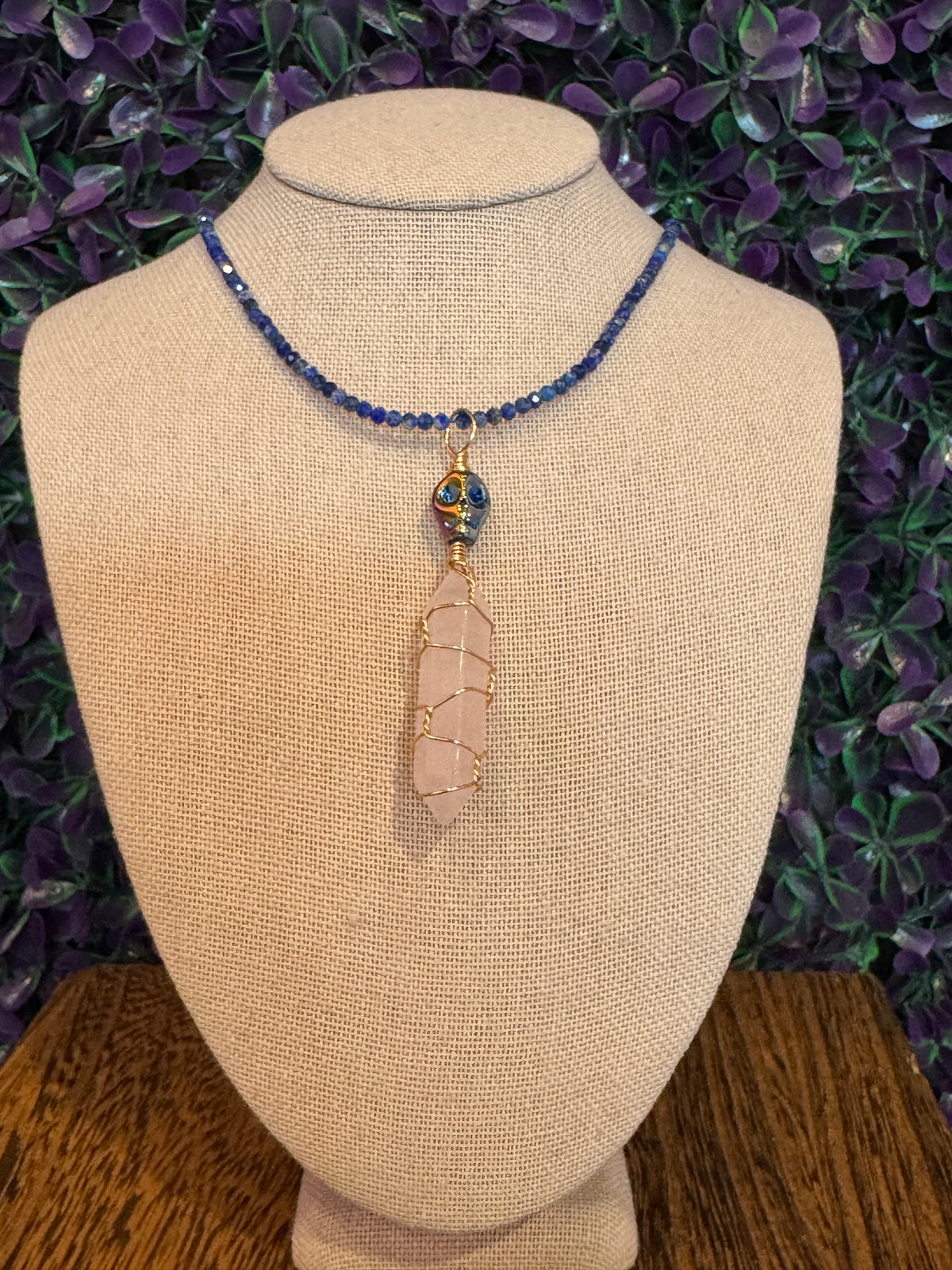 Pink Point and Skull Bead Necklace — product photo 2. A pale pink point wrapped in gold-tone wire, accented with a blue-and-gold skull bead and a blue faceted bead chain.