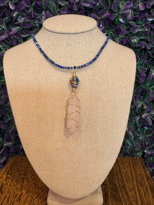 Pink Point and Skull Bead Necklace — product photo 2. A pale pink point wrapped in gold-tone wire, accented with a blue-and-gold skull bead and a blue faceted bead chain.