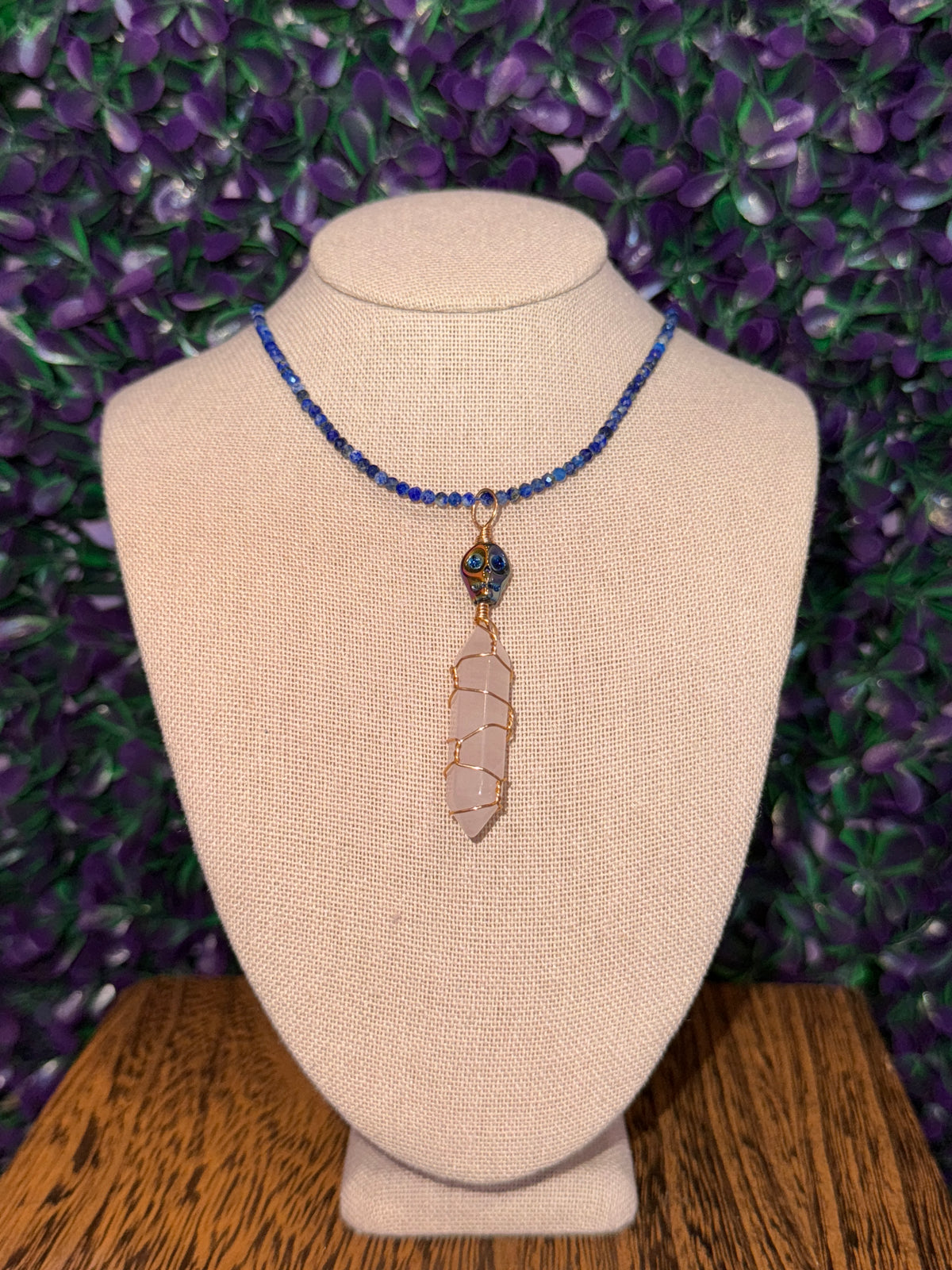 Pink Point and Skull Bead Necklace — product photo 3. A pale pink point wrapped in gold-tone wire, accented with a blue-and-gold skull bead and a blue faceted bead chain.