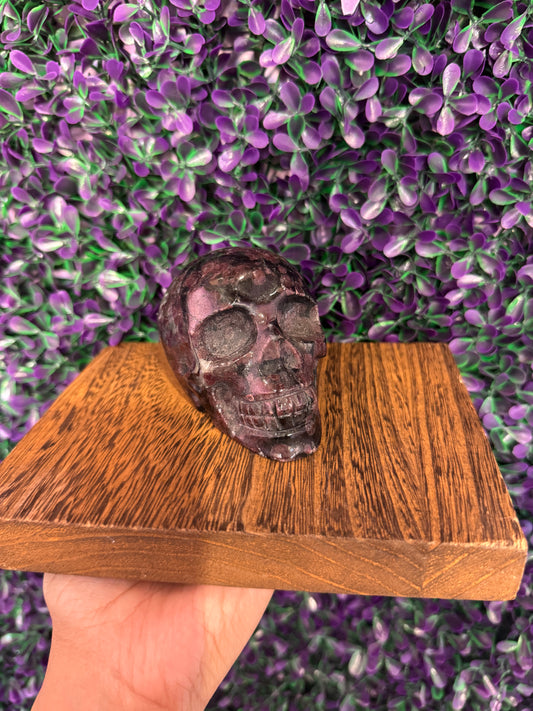 Purple-Gray Speckled Skull Carving — product photo 2. A polished skull carving with dark purple-gray coloring and pink-red speckles.