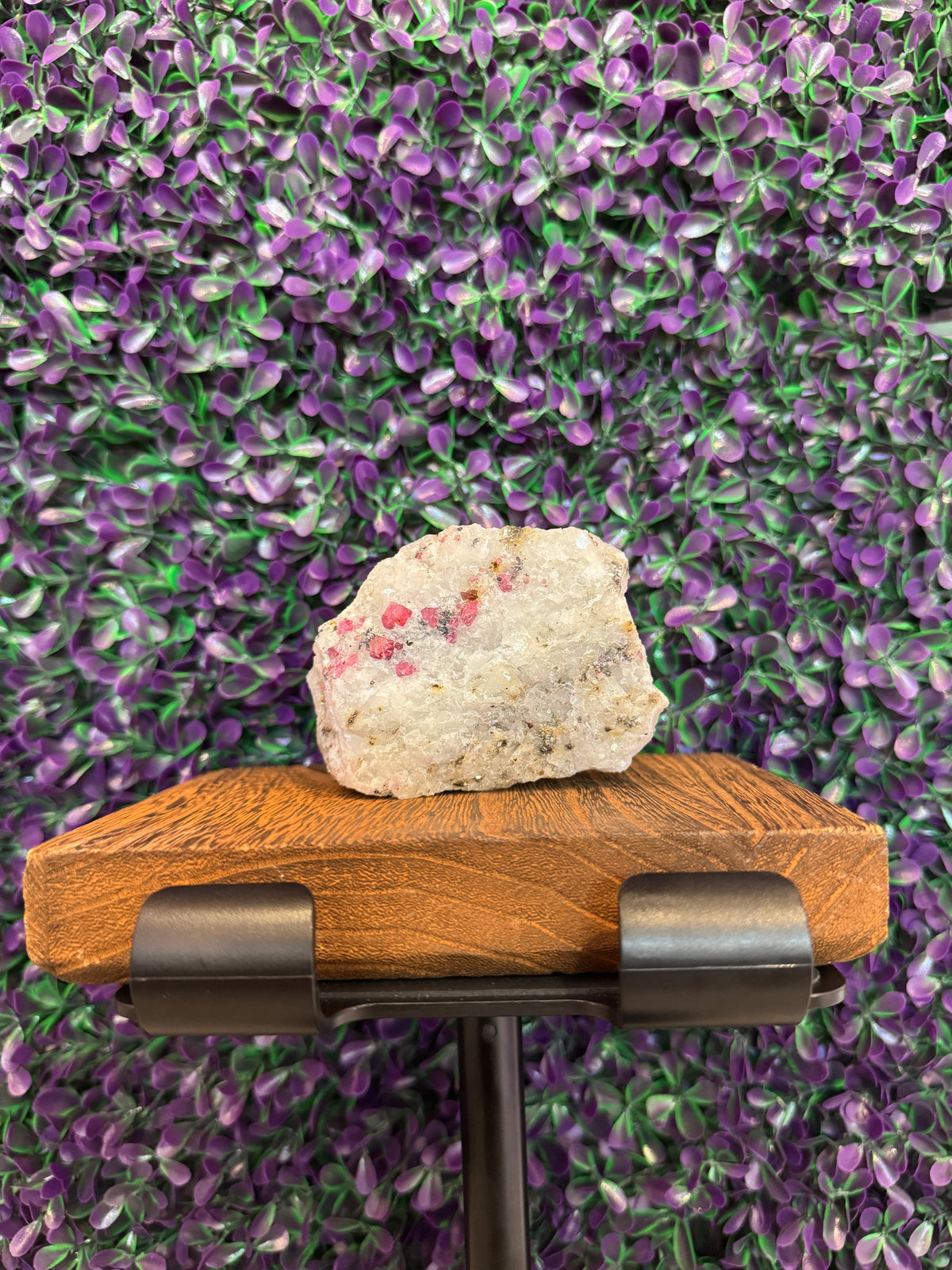 Ruby in marble specimen on a stand showing pink-red crystals in white matrix.