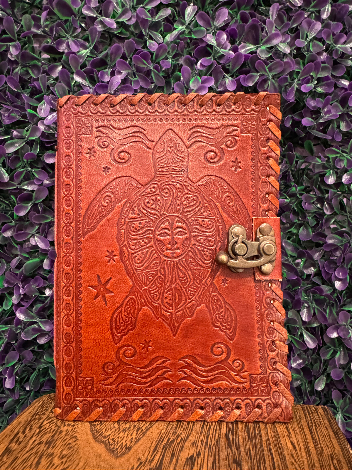 Red-brown embossed journal with a sea turtle, waves, and starfish design and a brass-tone clasp.