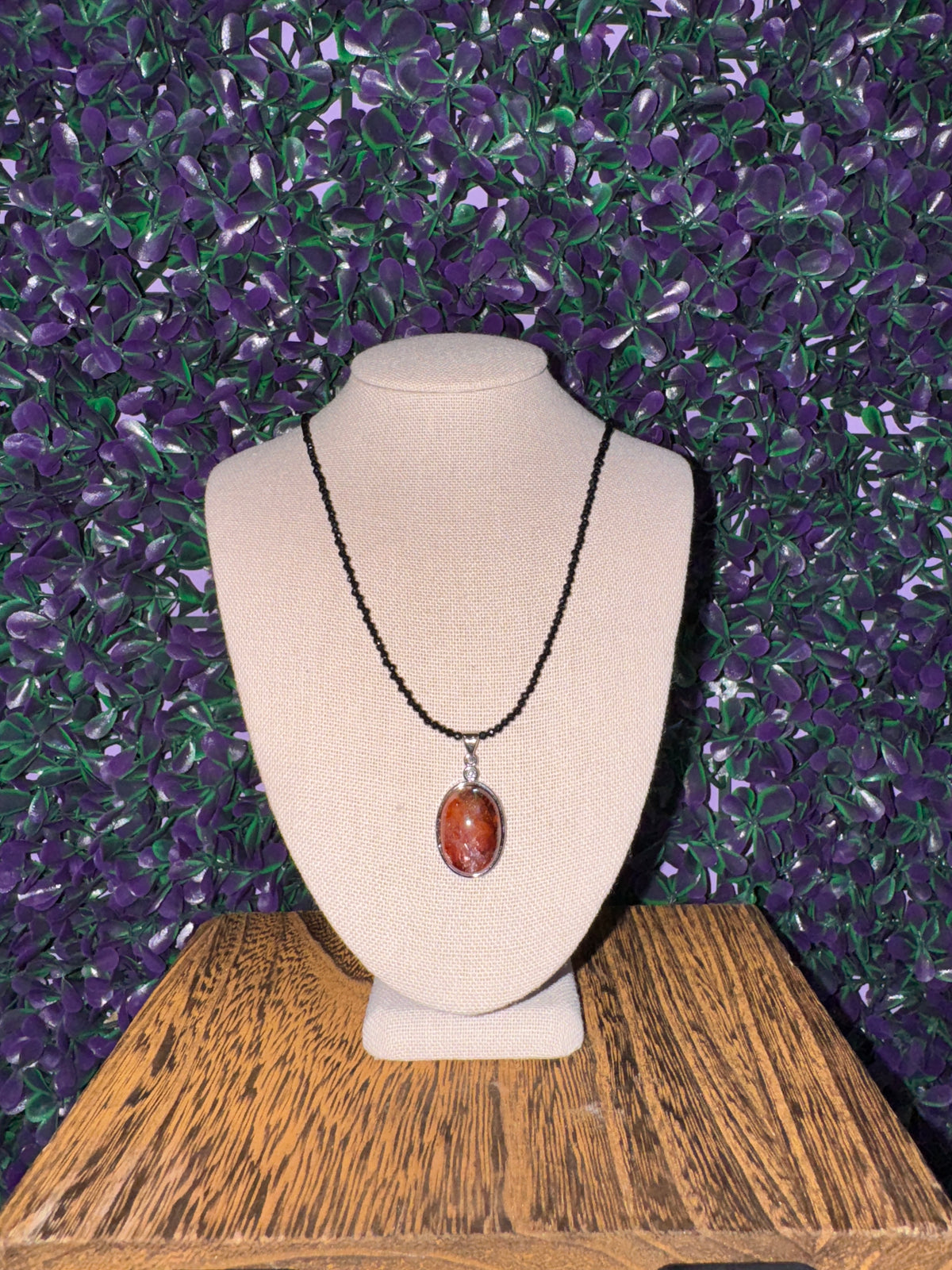 Sunstone and obsidian necklace on a linen bust in a separate shot.