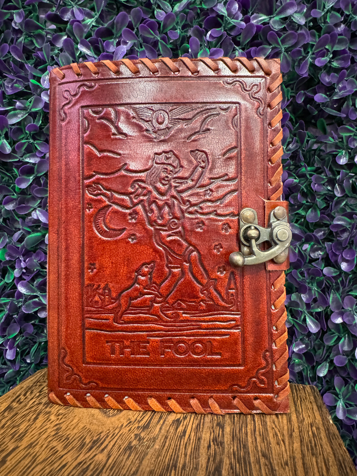 Red-brown embossed journal with The Fool tarot card design and a brass-tone clasp.