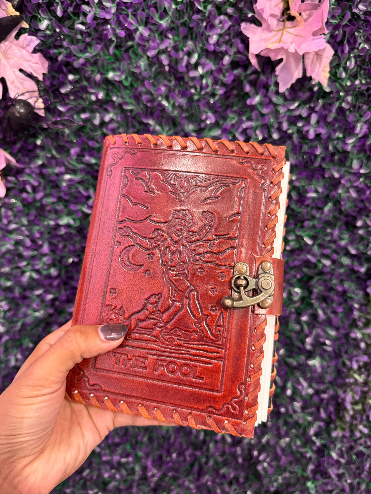 Hand holding The Fool tarot journal to show its size.