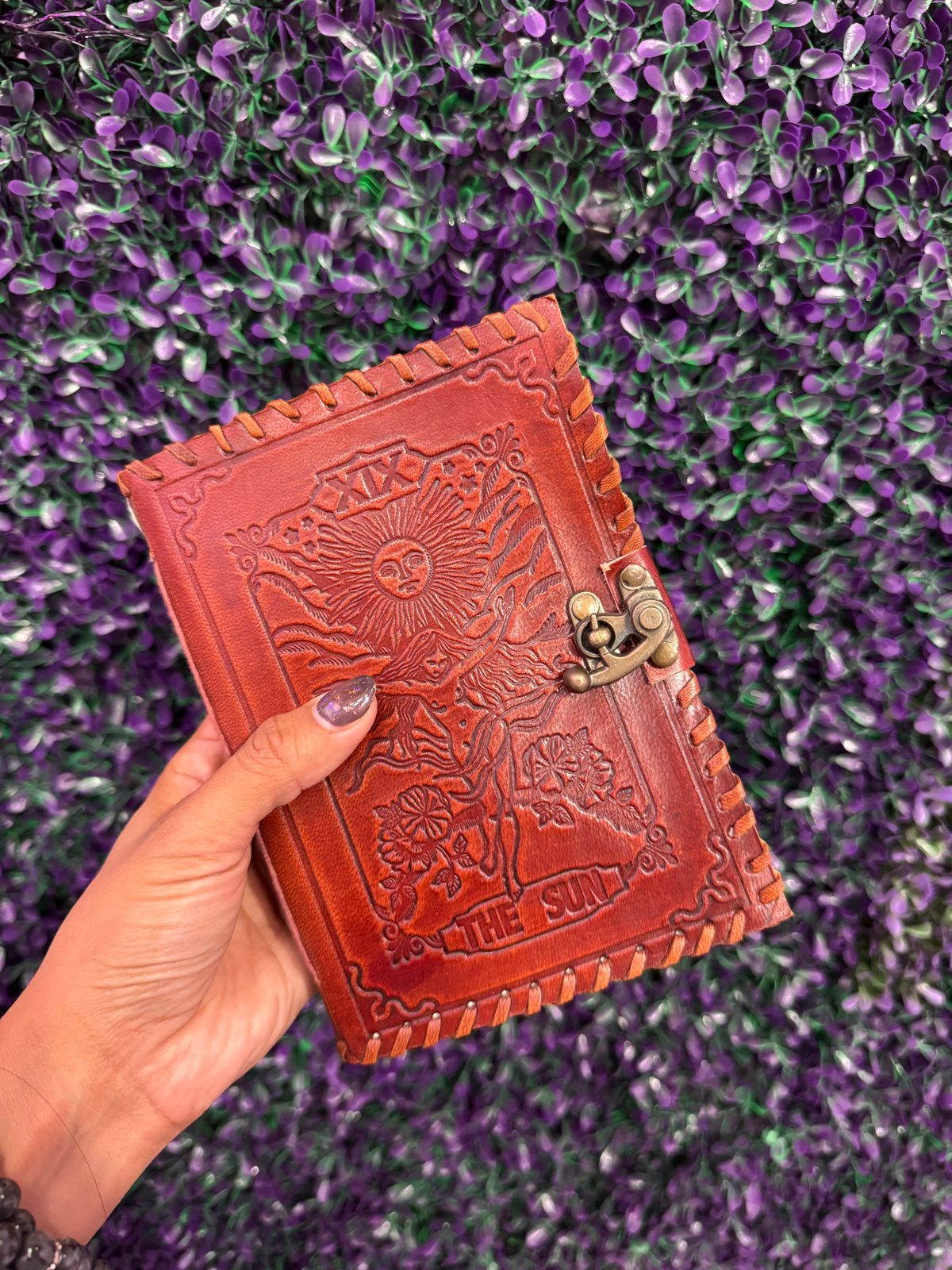 Hand holding The Sun tarot journal to show its size.